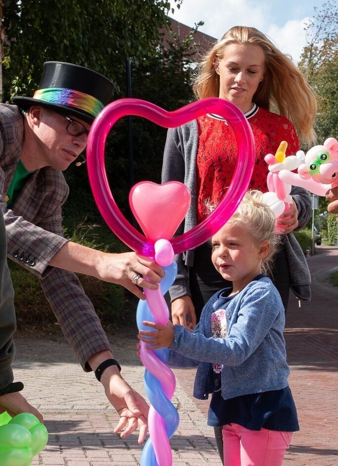 Lange Jan geeft een meisje een roze ballonhartstaf