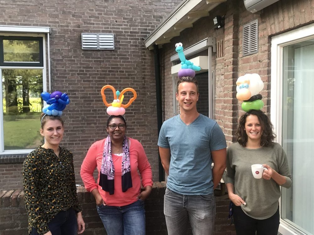 Vier collega's met haarbanden met ballonkunstwerken erop